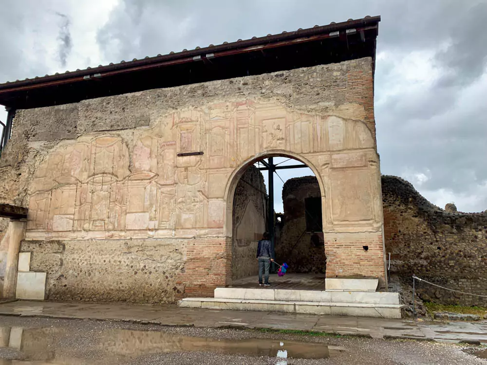 Stucco-covered exterior walls of the Stabian Baths in the Archaeological Park of Pompeii, Italy, showing faded textures, ancient Roman craftsmanship, and remnants of decorative detailing on the historic bathhouse.