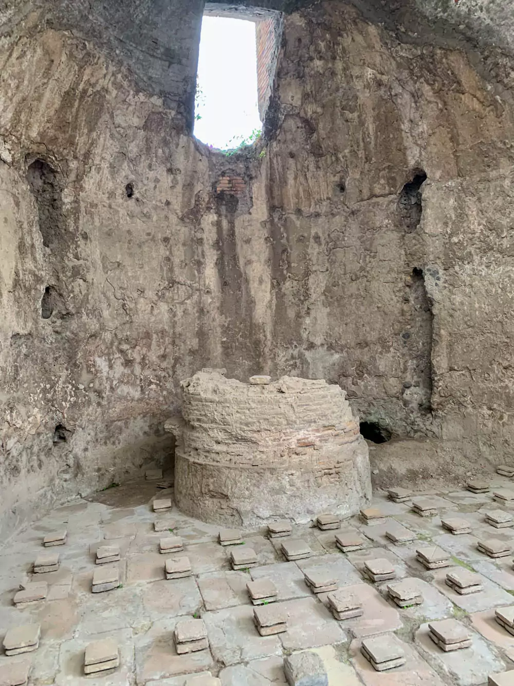 View looking west inside the men’s calidarium (Room 5) of the Stabian Baths in Pompeii, featuring a vaulted ceiling, wall niches, and remnants of Roman heating systems used in the ancient hot bath chamber.