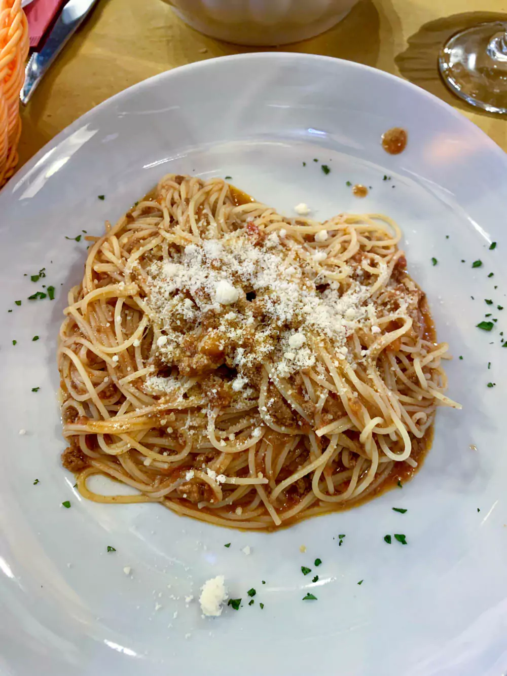 Plate of spaghetti served at a restaurant in Burano, Italy, with perfectly cooked pasta topped with a rich tomato sauce, captured in a cozy, colorful dining atmosphere.