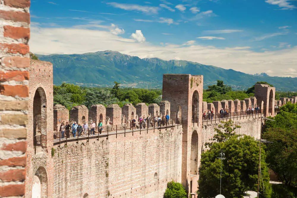 The city walls of Cittadella, Italy, a perfectly preserved circular medieval fortification made of red brick, with elevated walkways offering panoramic views of the historic town and surrounding countryside