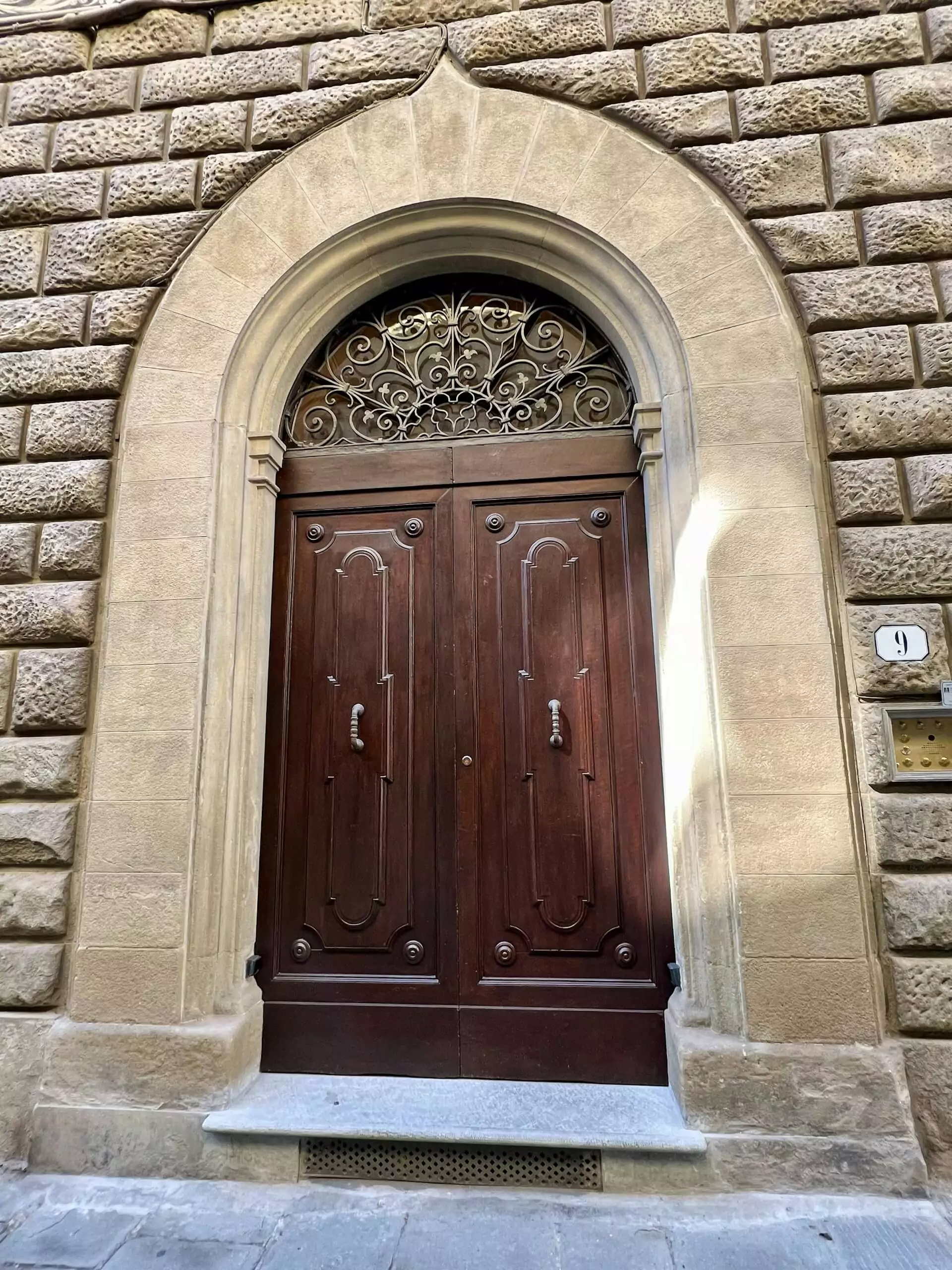 Ornate wooden door in Florence, Italy, featuring intricate carvings, aged patina, and a grand arched frame, reflecting the city’s rich Renaissance architectural heritage.