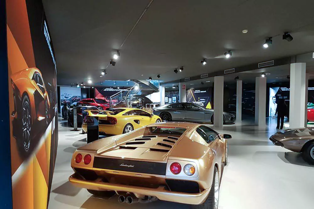 Lamborghini and Ferrari vehicles in a showroom, featuring sleek, high-performance sports cars with glossy finishes, bold styling, and iconic logos on display under bright lights