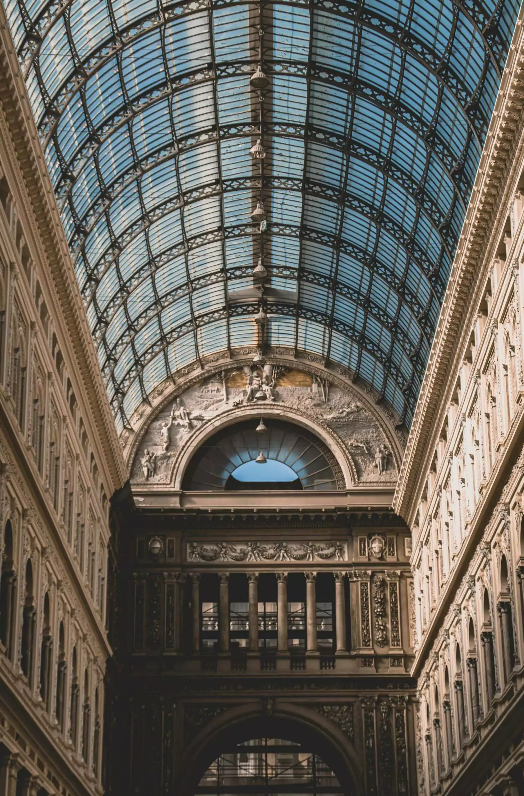 Ornate glass and iron dome ceiling of Galleria Umberto I in Naples, Italy, featuring intricate architectural details and intersecting barrel vaults that flood the elegant shopping gallery with natural light.