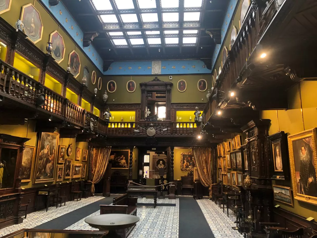 Interior of the Museo Civico Gaetano Filangieri in Naples, Italy, featuring elaborately decorated halls with classical sculptures, antique furnishings, and ornate ceilings inside the 15th-century Palazzo Como.