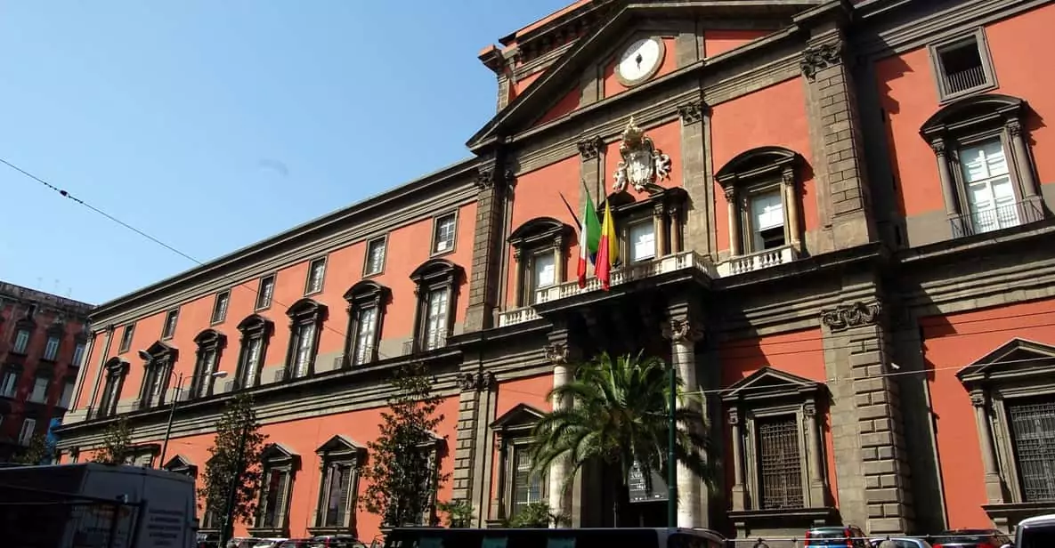 Exterior of the National Archaeological Museum in Naples, Italy, showcasing its red and gray neoclassical façade with arched windows and grand entrance, housing one of the world’s most important collections of Greco-Roman antiquities.