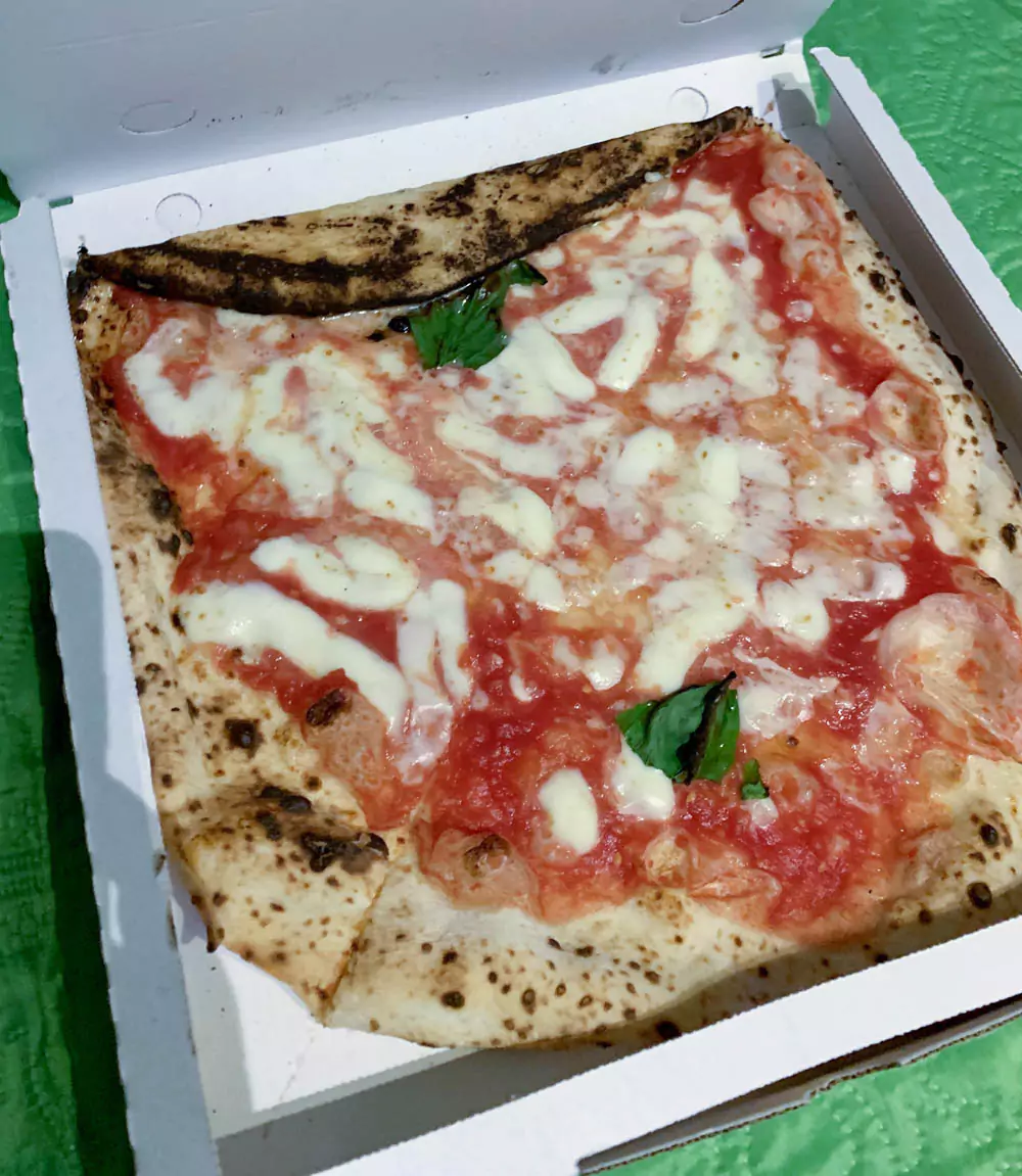 Classic Margherita pizza at L’Antica Pizzeria da Michele in Naples, Italy, featuring a thin, blistered crust topped with fresh tomato sauce, melted mozzarella, and basil leaves.