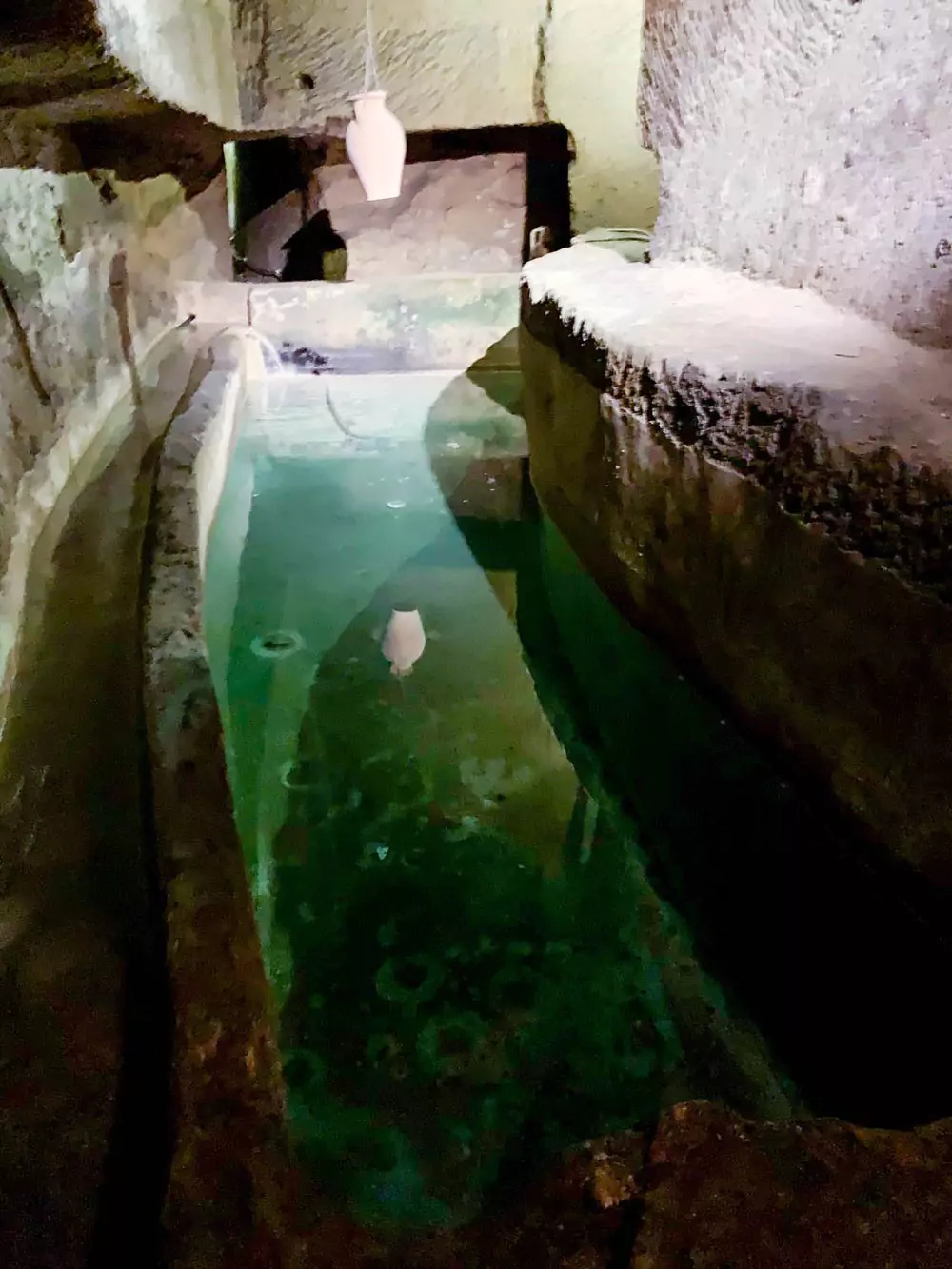 Still water reflecting stone walls inside the Naples Underground Tour, part of an ancient cistern system beneath the city’s historic center.