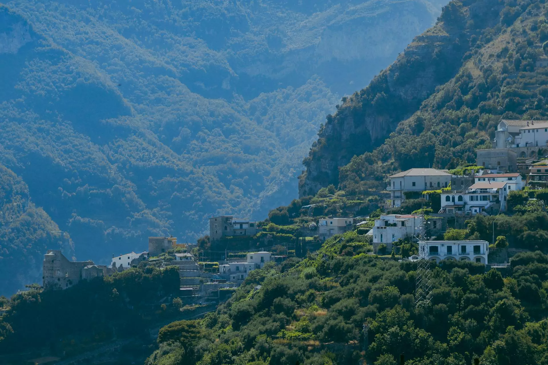 Buildings in Ravello, Italy, perched along the lush green mountainside of the Amalfi Coast, with terraced gardens, Mediterranean architecture, and sweeping views over the coastline below.