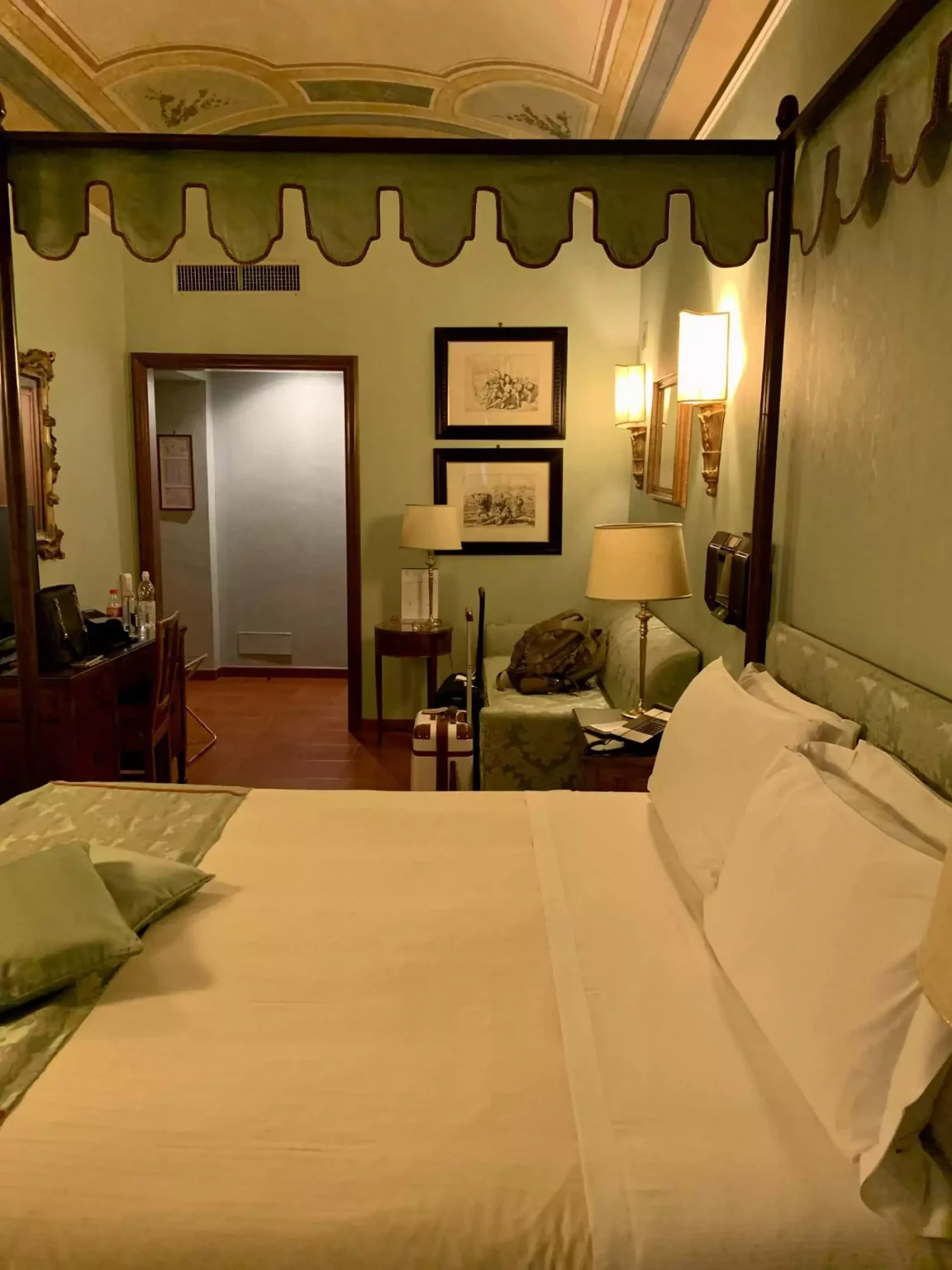 Cozy bedroom at Hotel Canada in Rome, Italy, featuring classic European decor with patterned wallpaper, elegant furniture, and warm lighting. The inviting space reflects a blend of traditional charm and comfortable hospitality.
