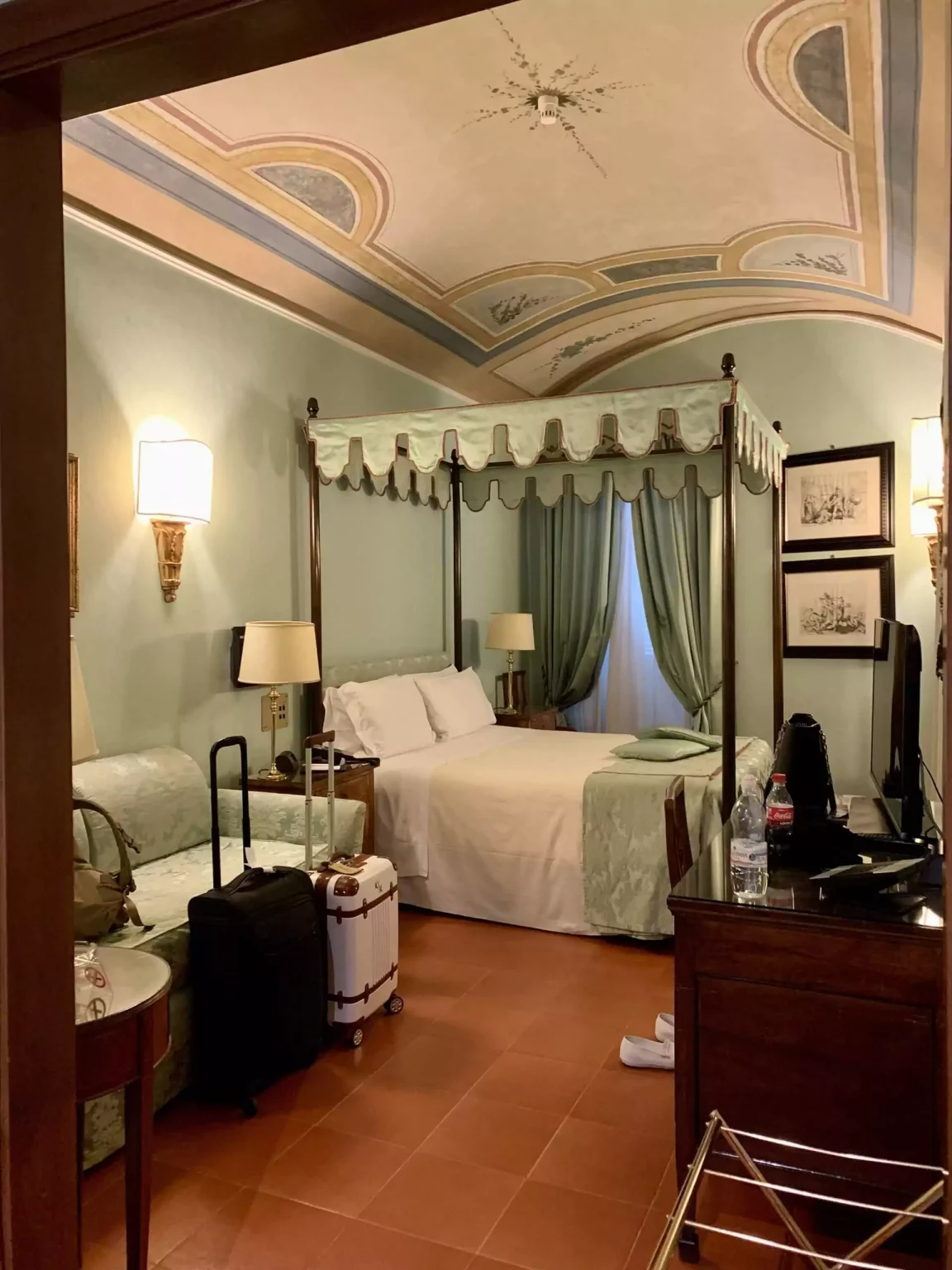 Cozy bedroom at Hotel Canada in Rome, Italy, featuring classic European decor with patterned wallpaper, elegant furniture, and warm lighting. The inviting space reflects a blend of traditional charm and comfortable hospitality.