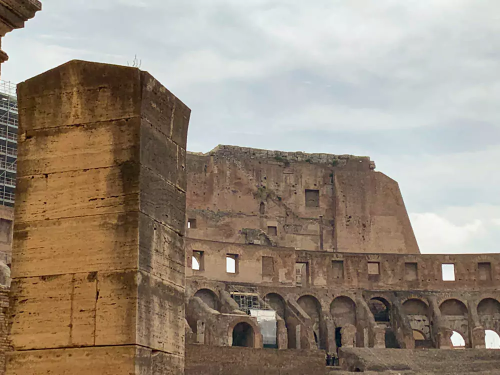 The ancient walls of the Colosseum in Rome, Italy, showcasing layers of weathered stone, arches, and exposed brickwork that reveal the enduring strength and architectural ingenuity of the Roman Empire.