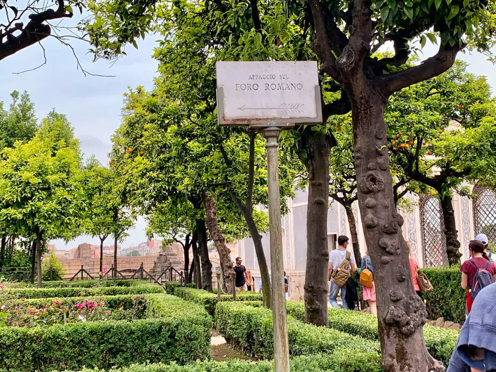 Sign for the Foro Romano located within the Palatine Hill gardens, surrounded by manicured greenery and historic stone pathways, guiding visitors toward the ancient Roman ruins.