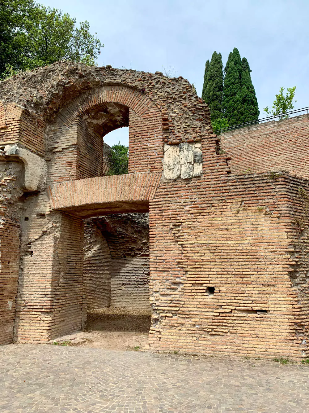 Ancient ruins on Palatine Hill in Rome, featuring weathered stone walls, columns, and arches, surrounded by lush greenery under a clear sky.