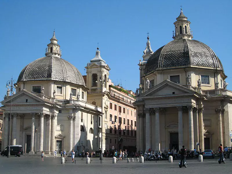 Outside view of Santa Maria del Popolo church in Rome, Italy, showcasing its stone façade with a circular rose window, arched doorway, and classic Renaissance architectural details against a clear sky. - credit: tripadvisor