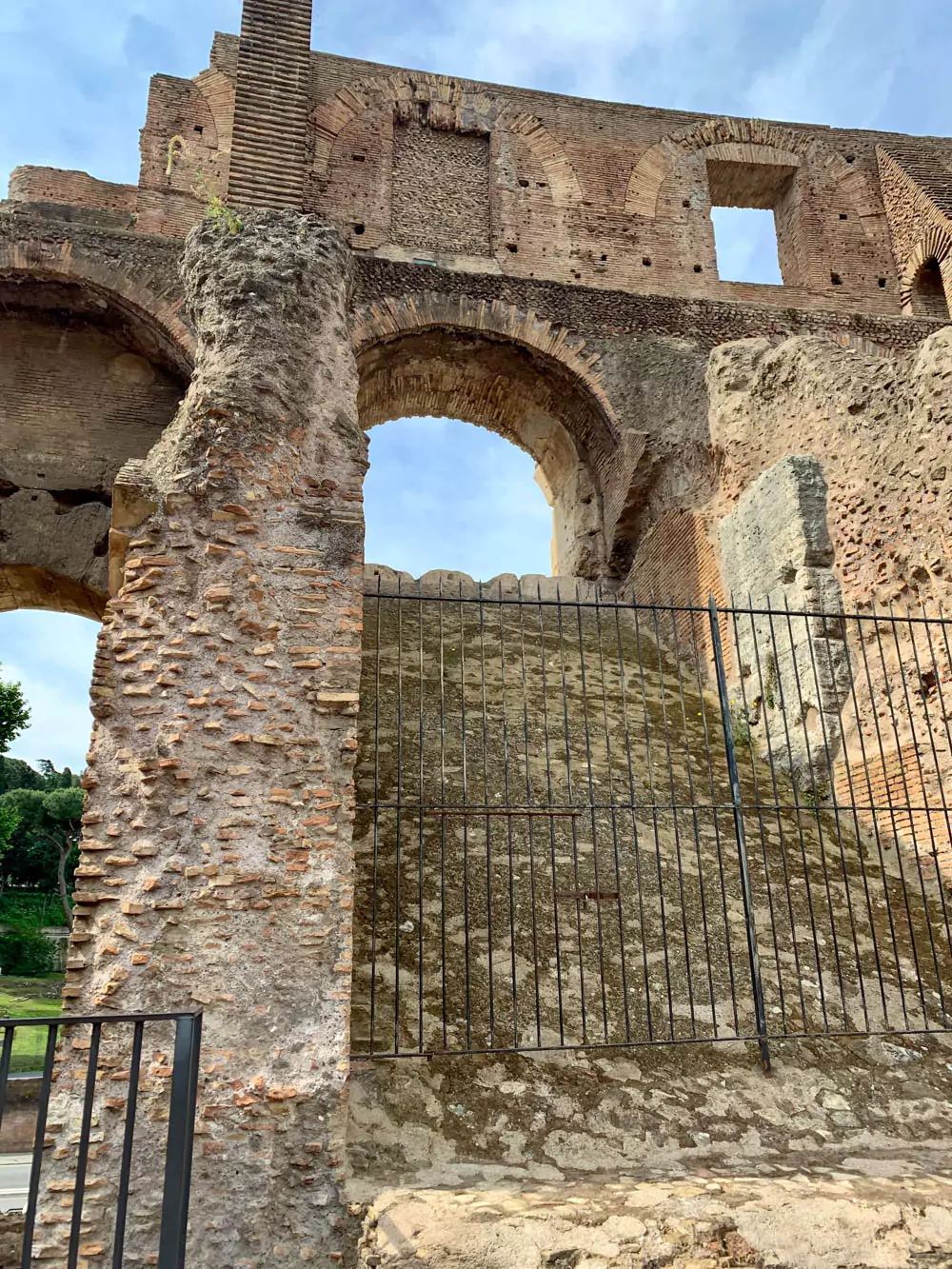 Detailed view of the upper tier of the Colosseum, featuring weathered stone arches, intricate brickwork, and historic architectural details illuminated by sunlight.