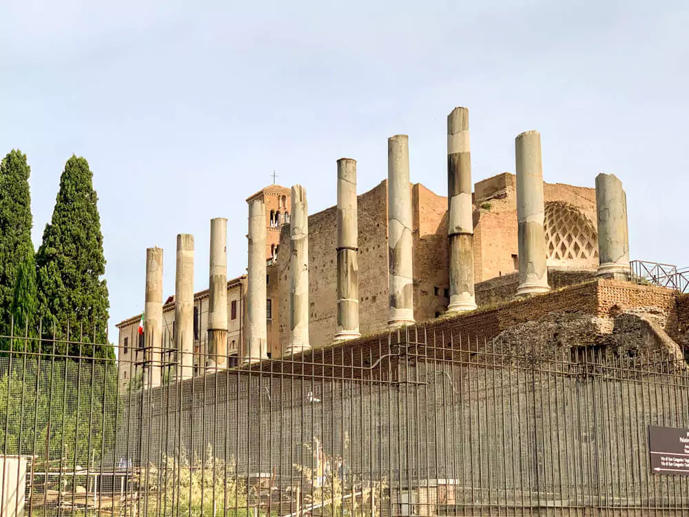 Standing columns of the Temple of Venus and Rome in the Roman Forum, showcasing ancient Roman architecture with tall, weathered stone pillars against a backdrop of ruins and open sky.