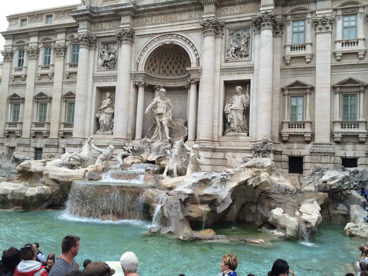 Detailed view of the statues at the Trevi Fountain in Rome, Italy, featuring Oceanus at the center flanked by tritons and horses emerging from the water. The intricate Baroque sculptures and flowing water create a dramatic and majestic scene.