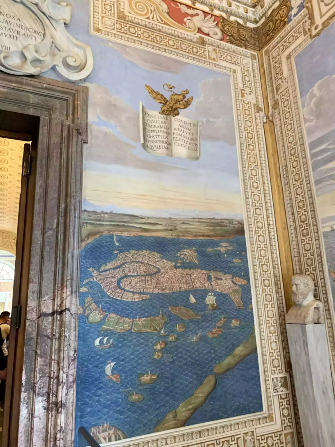 Gallery of Maps in the Vatican Museums, Rome, featuring vibrant 16th-century frescoes of Italian regions painted along the corridor walls. The arched ceiling is richly decorated with ornate gold and artwork, creating a grand and immersive historical experience.