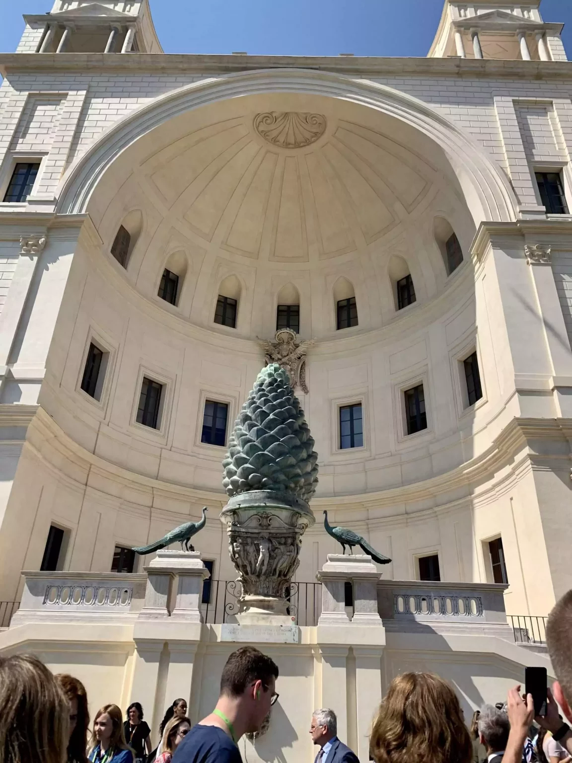 The Fontana della Pigna, or simply Pigna, at the Vatican in Rome, featuring a massive bronze pinecone sculpture set atop a decorative pedestal. Flanked by peacocks and classical architectural elements, the ancient fountain adds a symbolic touch to the Cortile della Pigna courtyard.