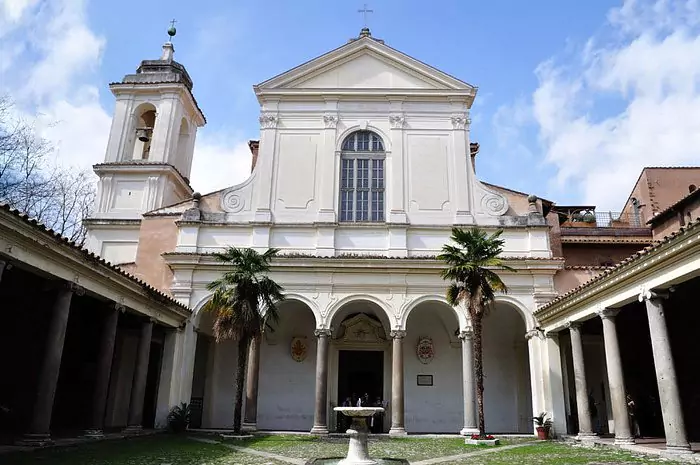Exterior of the Basilica of San Clemente in Rome, Italy, featuring a modest brick façade with arched windows, a bell tower, and a peaceful courtyard leading into the historic multi-layered church.