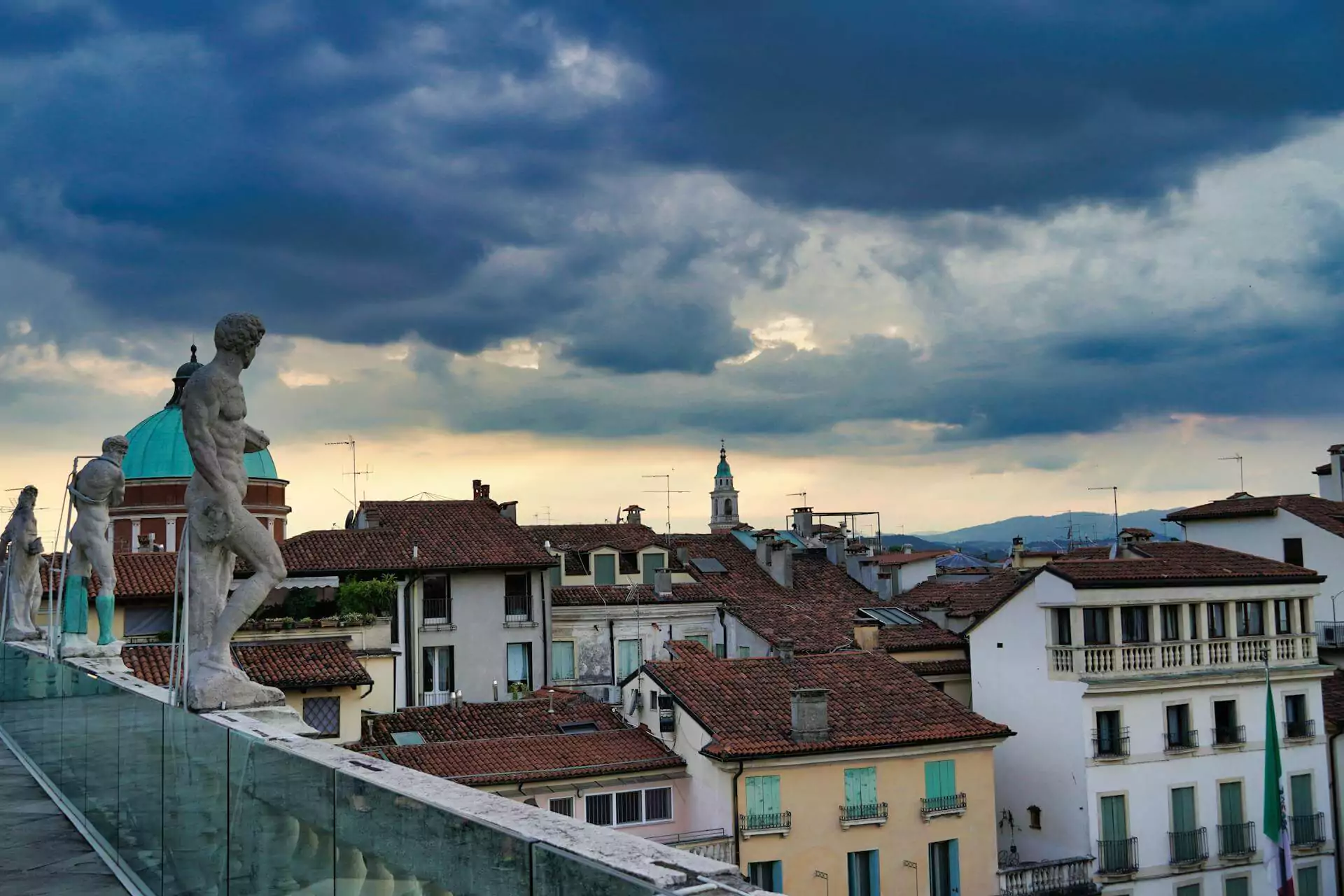 Terrace of the Cathedral in Vicenza, Italy, offering panoramic views of the city's red-tiled rooftops and historic architecture under a dramatic evening sky
