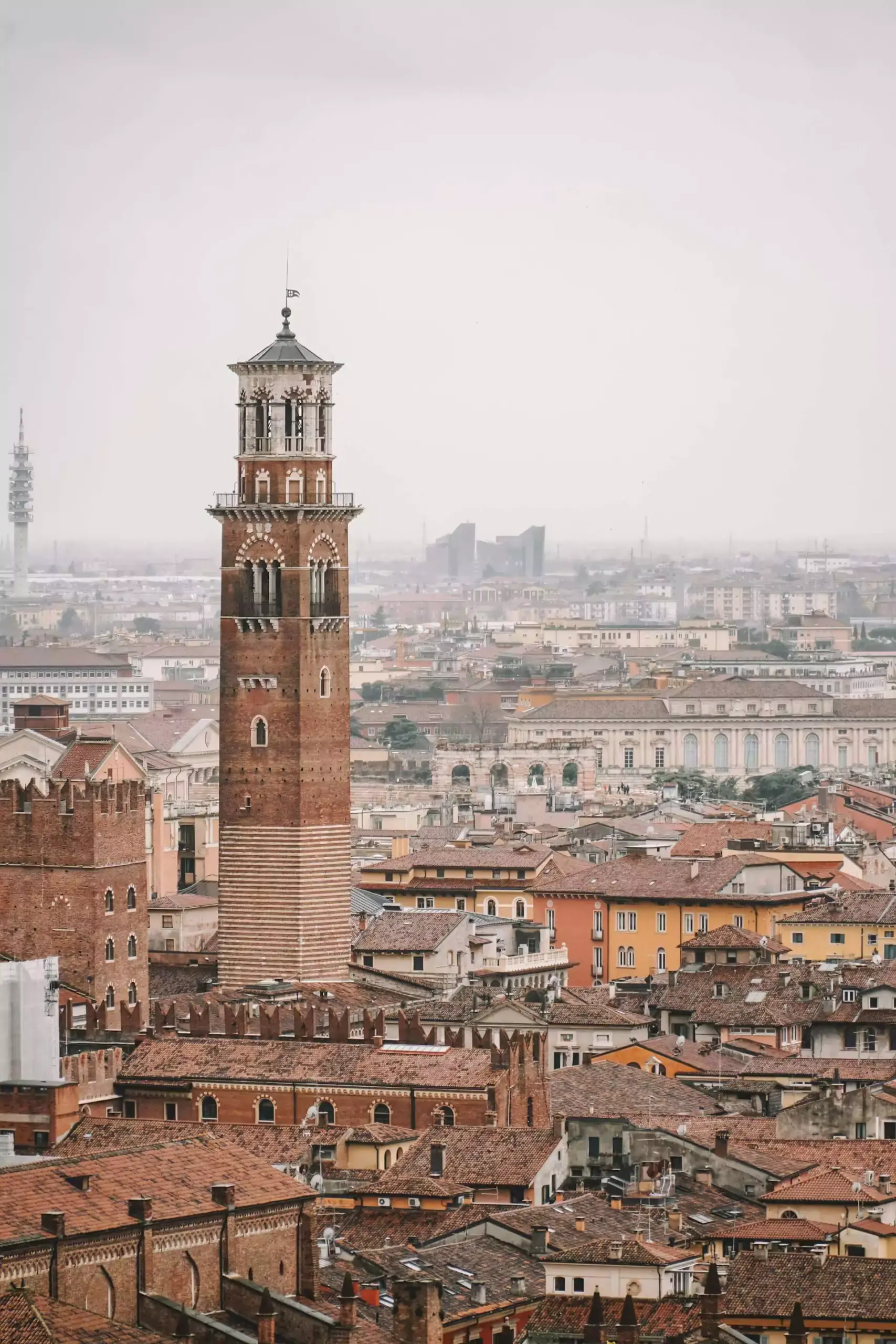 Torre dei Lamberti in Verona, Italy, an 84-meter medieval tower with a distinctive octagonal bell chamber, constructed from red brick and white marble, offering panoramic views of the historic city center