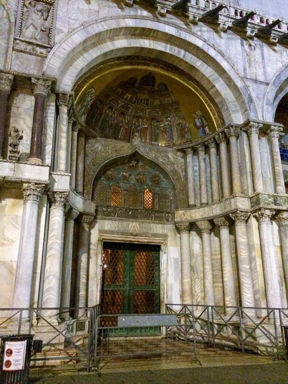 Entrance to St. Mark’s Basilica in Venice, featuring ornate arches decorated with intricate mosaics, detailed carvings, and golden accents, welcoming visitors into the historic church.