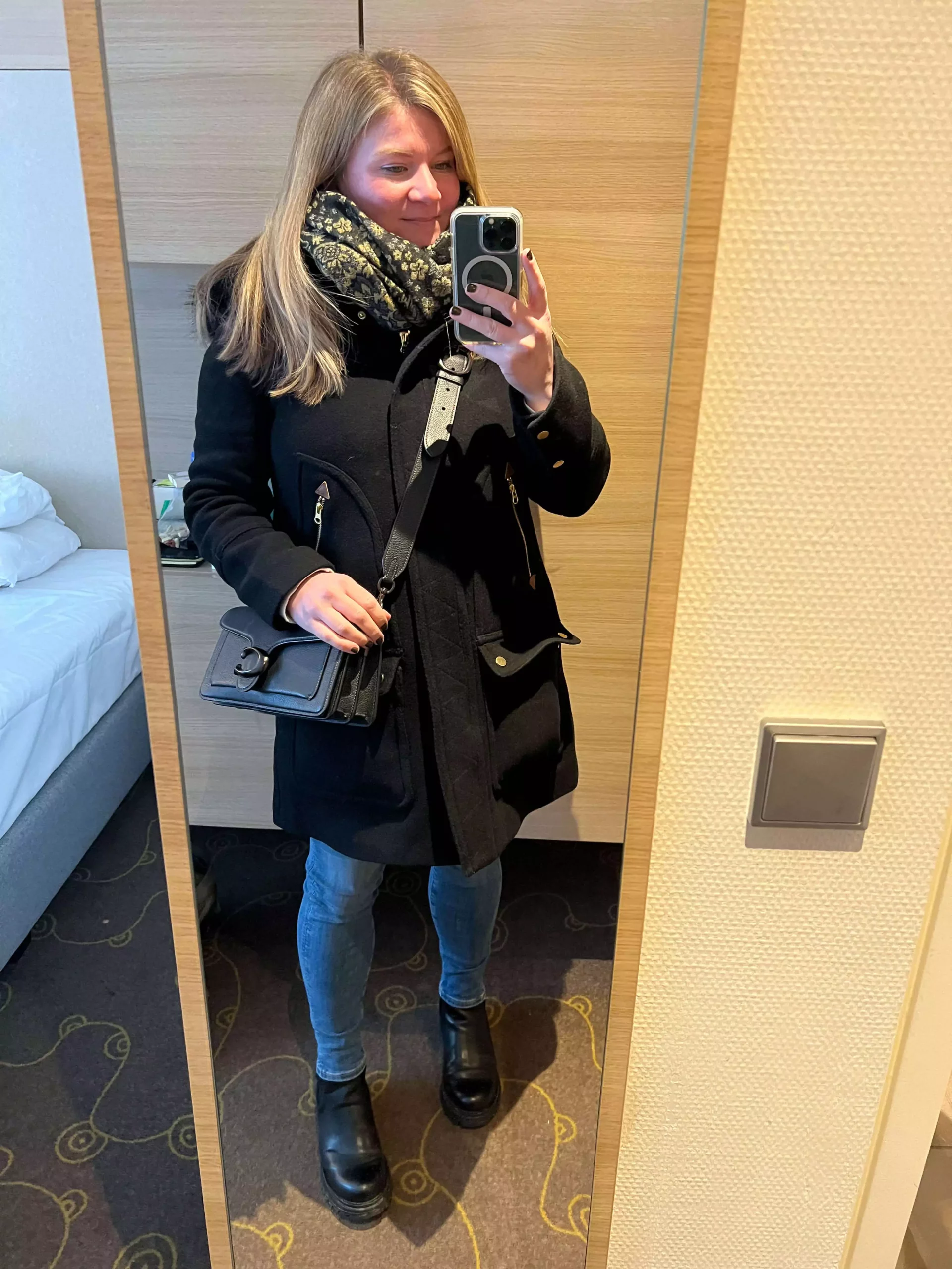 Katie dressed in skinny jeans, black boots, a black jacket, and carrying a Coach purse, ready for a winter dinner in Salzburg. Her chic, cold-weather outfit blends cozy style with a touch of elegance against the historic city backdrop.
