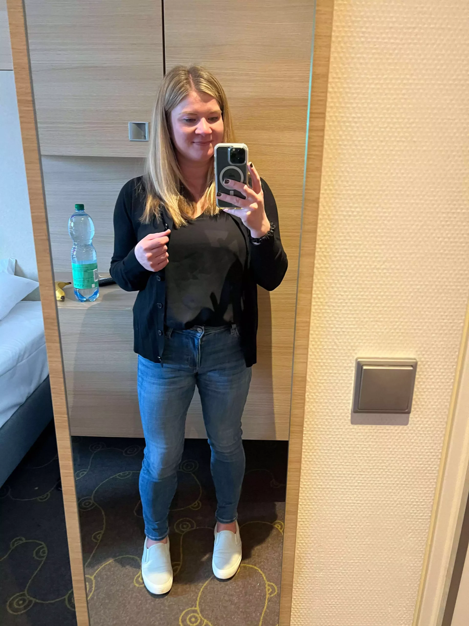 Katie dressed in skinny jeans, slip-on sneakers, a black top, and a black cardigan, ready for a comfortable train ride through Europe. Her casual yet stylish outfit blends practicality with a relaxed, travel-ready vibe.