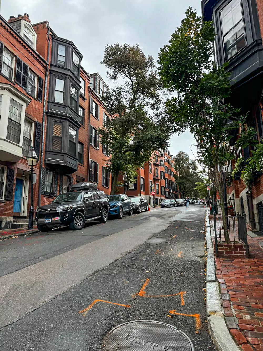 Charming cobblestone street in Boston’s Beacon Hill neighborhood, lined with historic brick row houses, black shutters, and vintage-style street lamps. The picturesque scene captures the timeless elegance and colonial character of the area.