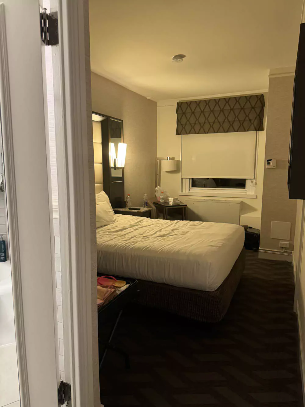 View of a Hilton Boston hotel room from the doorway, featuring a large bed, modern decor, and the iconic Wicked Queen window letting in natural light.
