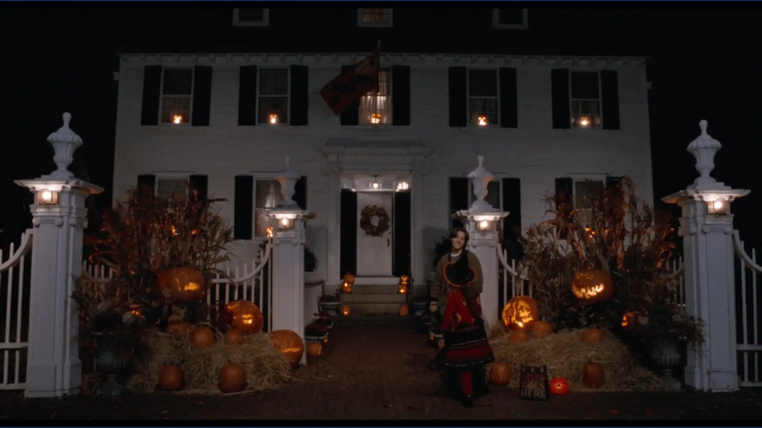 A nighttime view of the Ropes Mansion in Salem, known as Allison’s house in Hocus Pocus, with soft exterior lighting highlighting its white colonial facade and black shutters. The dark sky and subtle illumination create a mysterious, cinematic atmosphere.