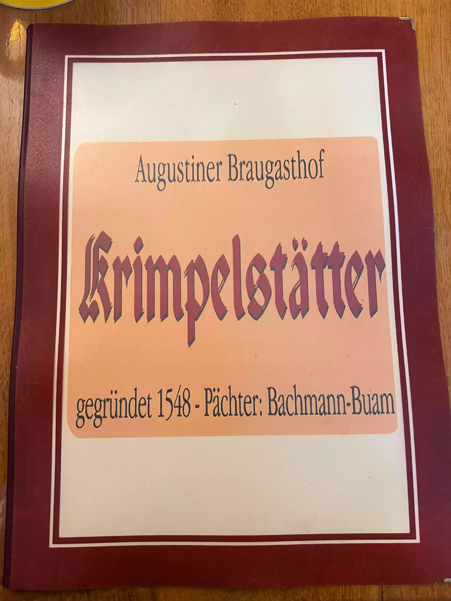 The menu at Augustiner Bräugasthof Krimpelstätter in Salzburg, Austria, displayed in German with traditional offerings like sausages, schnitzel, goulash, and roasted potatoes. The rustic design and classic font reflect the tavern’s old-world charm and authentic Austrian fare.