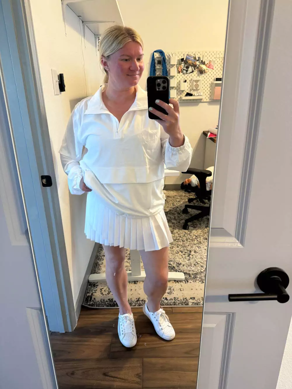 White skort, zip jacket, sneakers, and accessories.