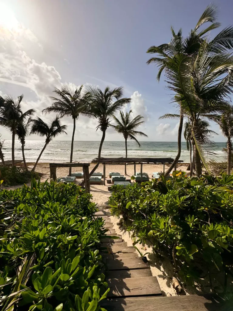 Stunning beach view from a hotel in Tulum, Mexico, overlooking white sand, turquoise Caribbean waters, and swaying palm trees—ideal for a relaxing 3-day Tulum getaway.