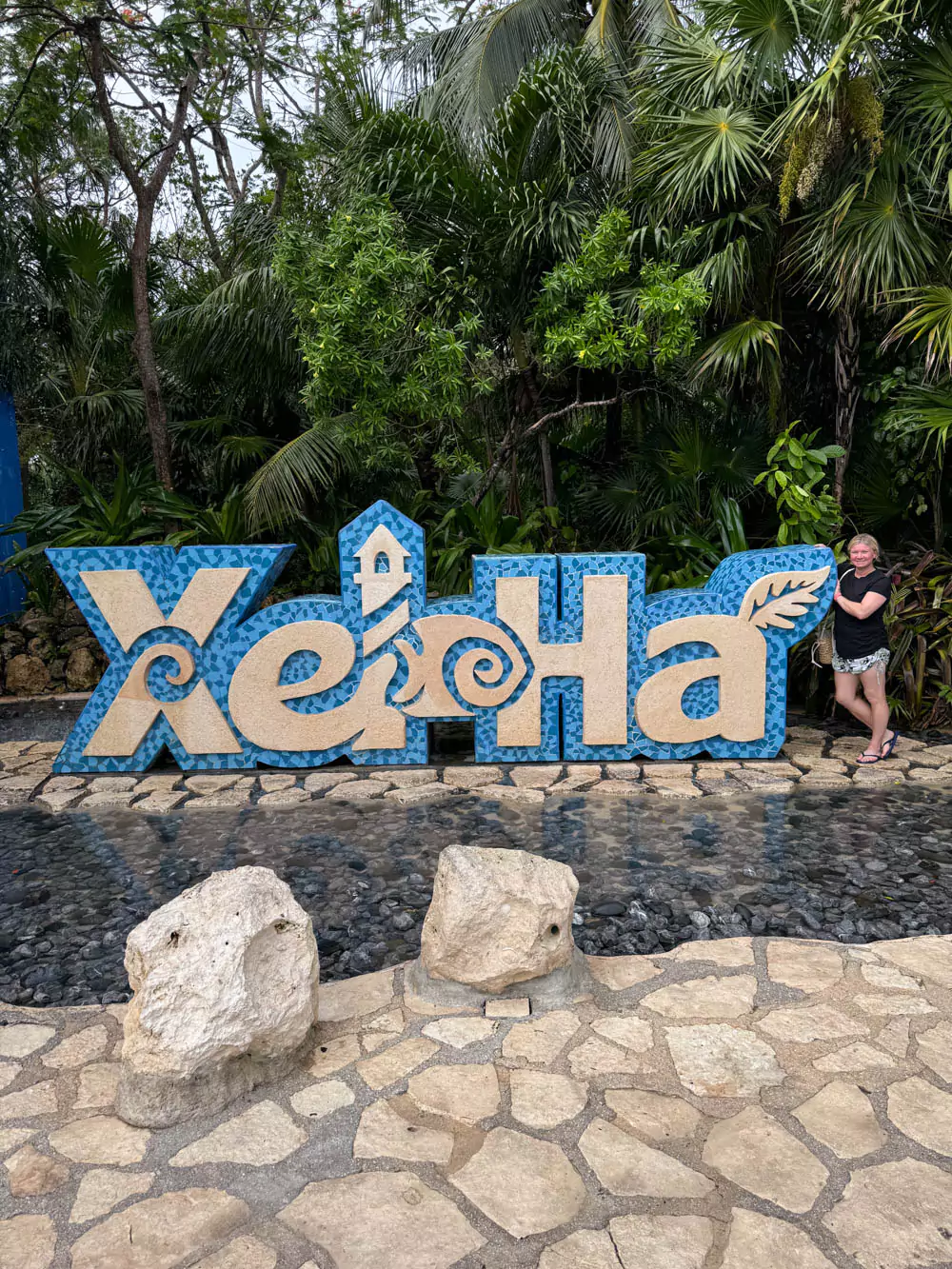 Katie standing at the entrance of Xel-Há, with the park’s colorful sign and lush tropical landscaping behind her. She’s ready for a day of adventure in the natural aquatic park, surrounded by vibrant greenery and excitement.
