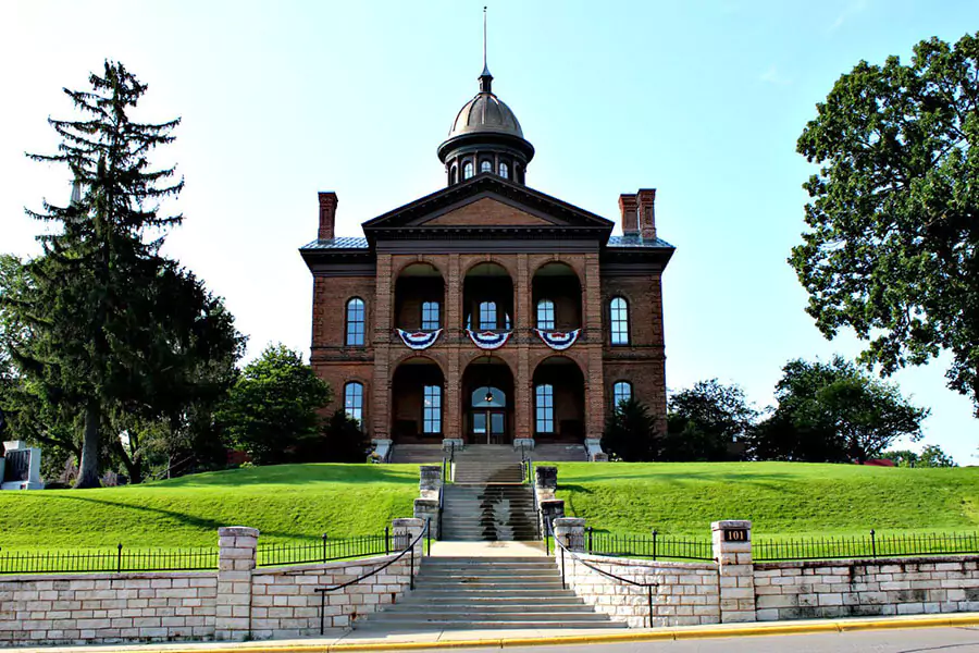 Historic Washington County Courthouse in Stillwater, Minnesota, featuring a grand brick facade, white dome, and stately columns. Set on a hilltop surrounded by trees, the courthouse is a landmark of civic pride and 19th-century architecture.