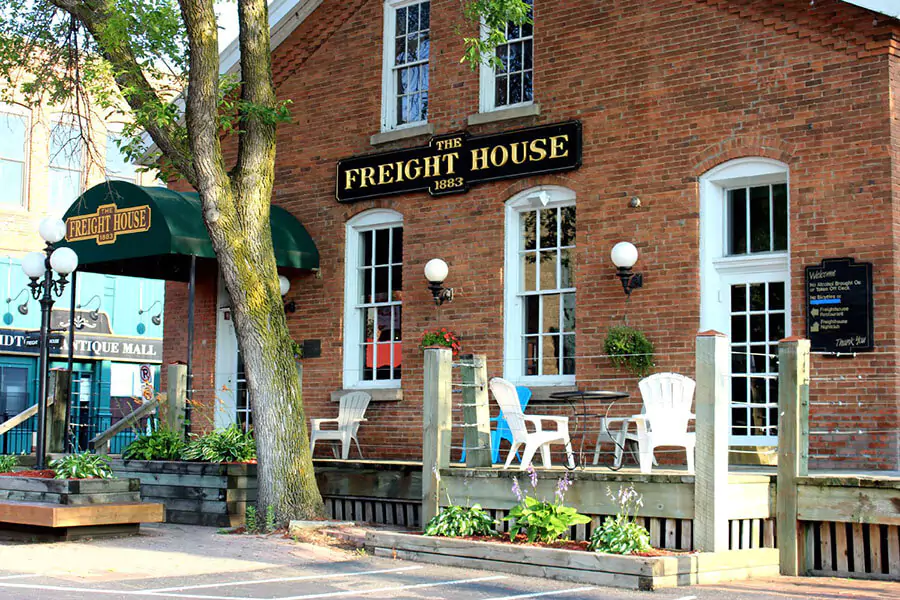 The Freight House in Stillwater, Minnesota, a historic red-brick building with large windows and a riverfront patio. Once a train depot, it now serves as a restaurant and gathering spot, blending old railroad charm with scenic views.