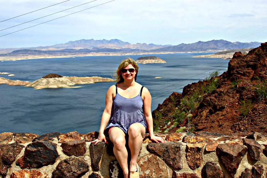 Katie standing by Lake Mead on a sunny day, with clear blue water and rocky desert landscapes stretching out behind her.