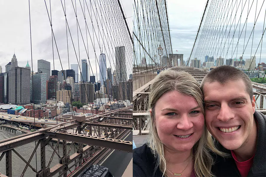 Katie and Zack standing together on the Brooklyn Bridge in New York City, smiling with the bridge’s iconic cables and stone arches behind them. The city skyline peeks through in the background, capturing a classic NYC moment.