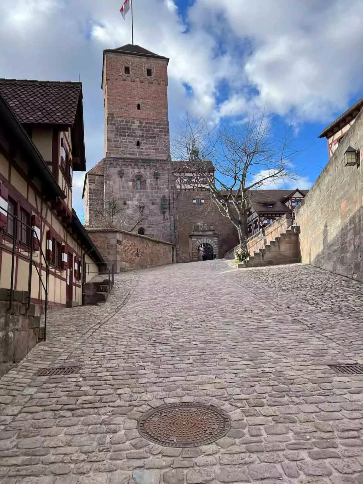 Steep cobblestone walkway leading up to the Imperial Castle of Nuremberg, flanked by historic stone walls and medieval towers, creating a dramatic and authentic approach to the fortress.