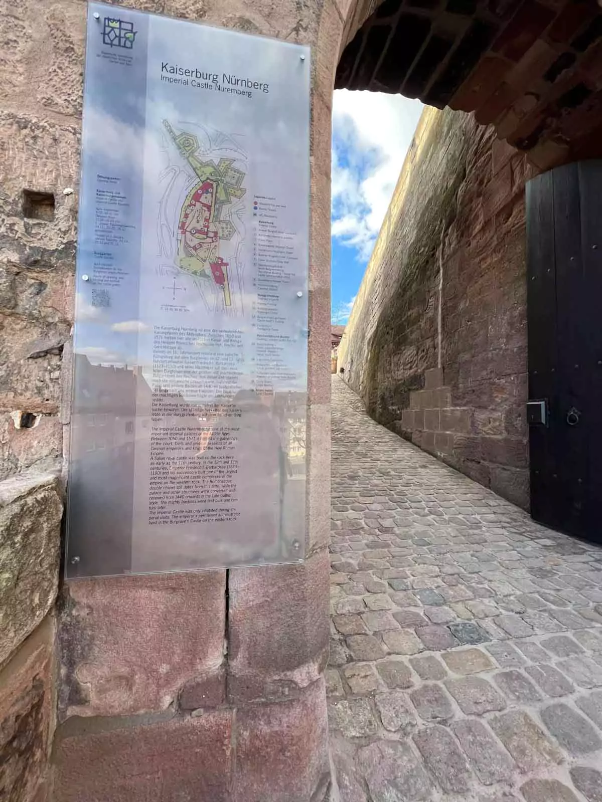 Entrance to Nuremberg Castle in Germany, featuring a fortified stone gate with a wooden drawbridge, arched entryway, and medieval towers set against the historic castle walls.