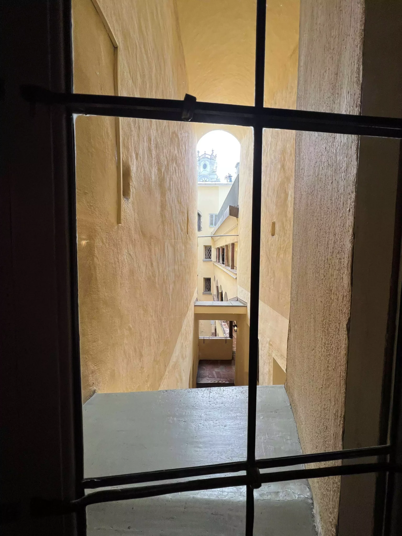 A peek into the quiet courtyard at Mozart’s Birthplace in Salzburg reveals pastel yellow walls, arched windows, and a cobblestone path. The serene space offers a charming glimpse into the historic building’s inner world.
