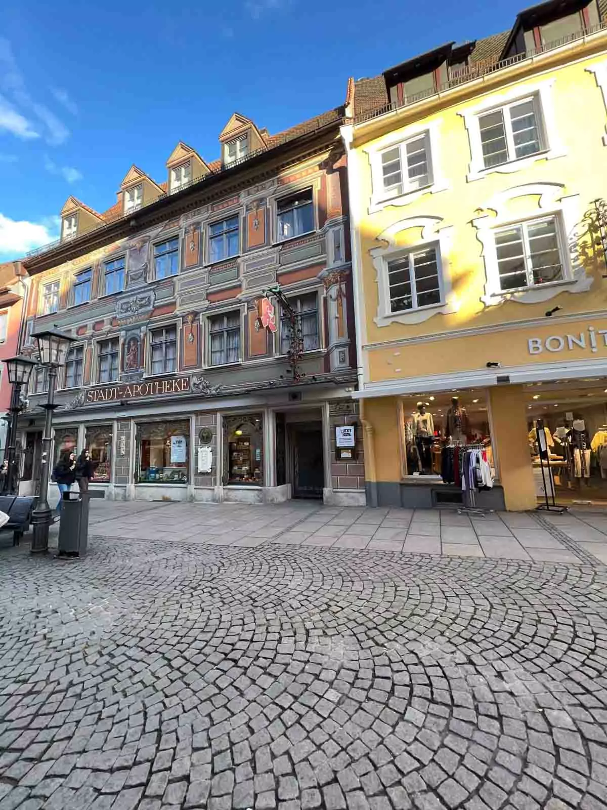 Row of colorful historic buildings in Füssen, Germany, with pastel facades, painted details, and alpine-style architecture lining a charming cobblestone street.