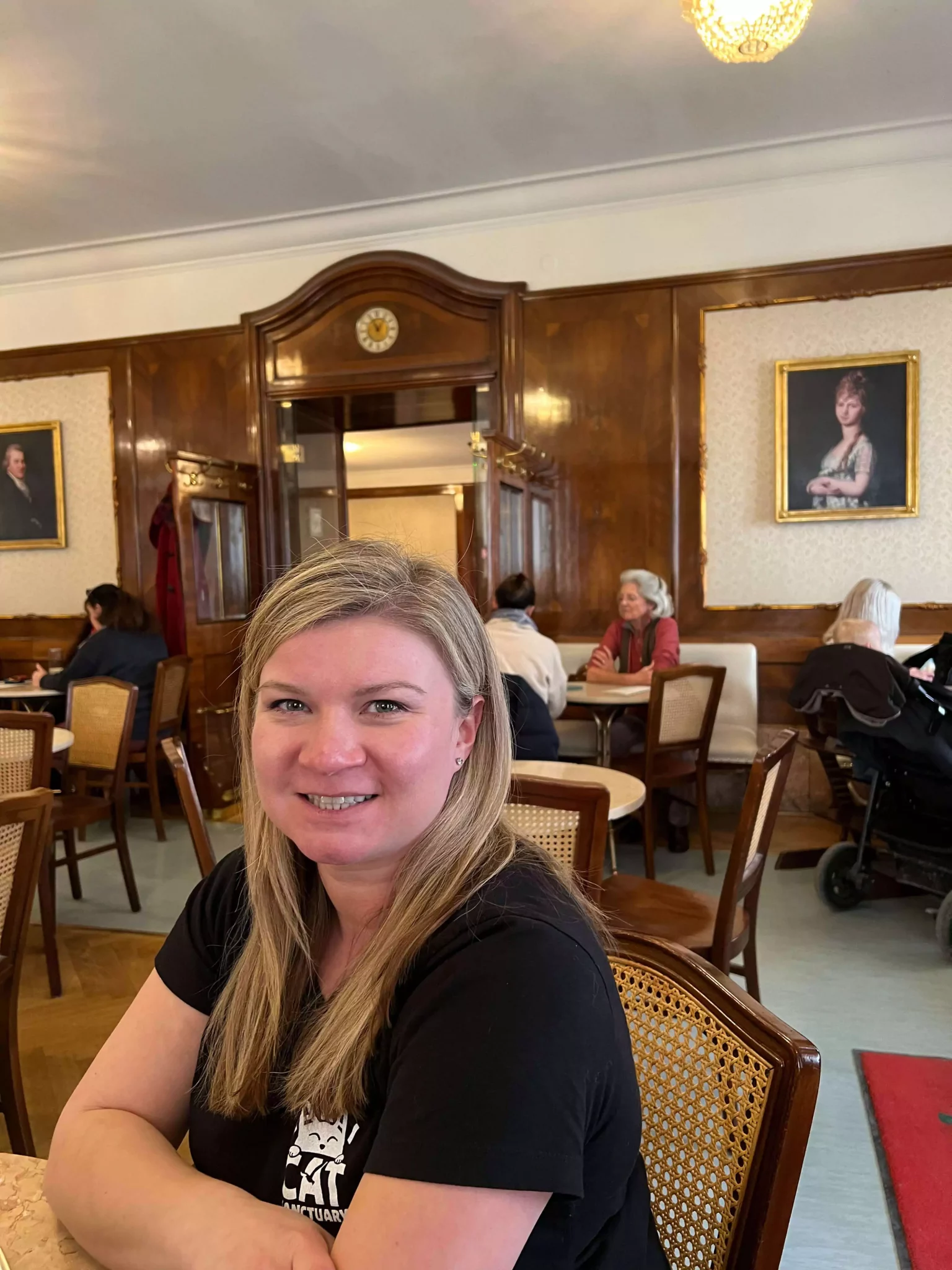 Katie sits at a table at Café Tomaselli in Salzburg, Austria, surrounded by the café’s refined, old-world charm. Her relaxed posture and the classic setting capture the timeless vibe of one of the city's most iconic coffeehouses.
