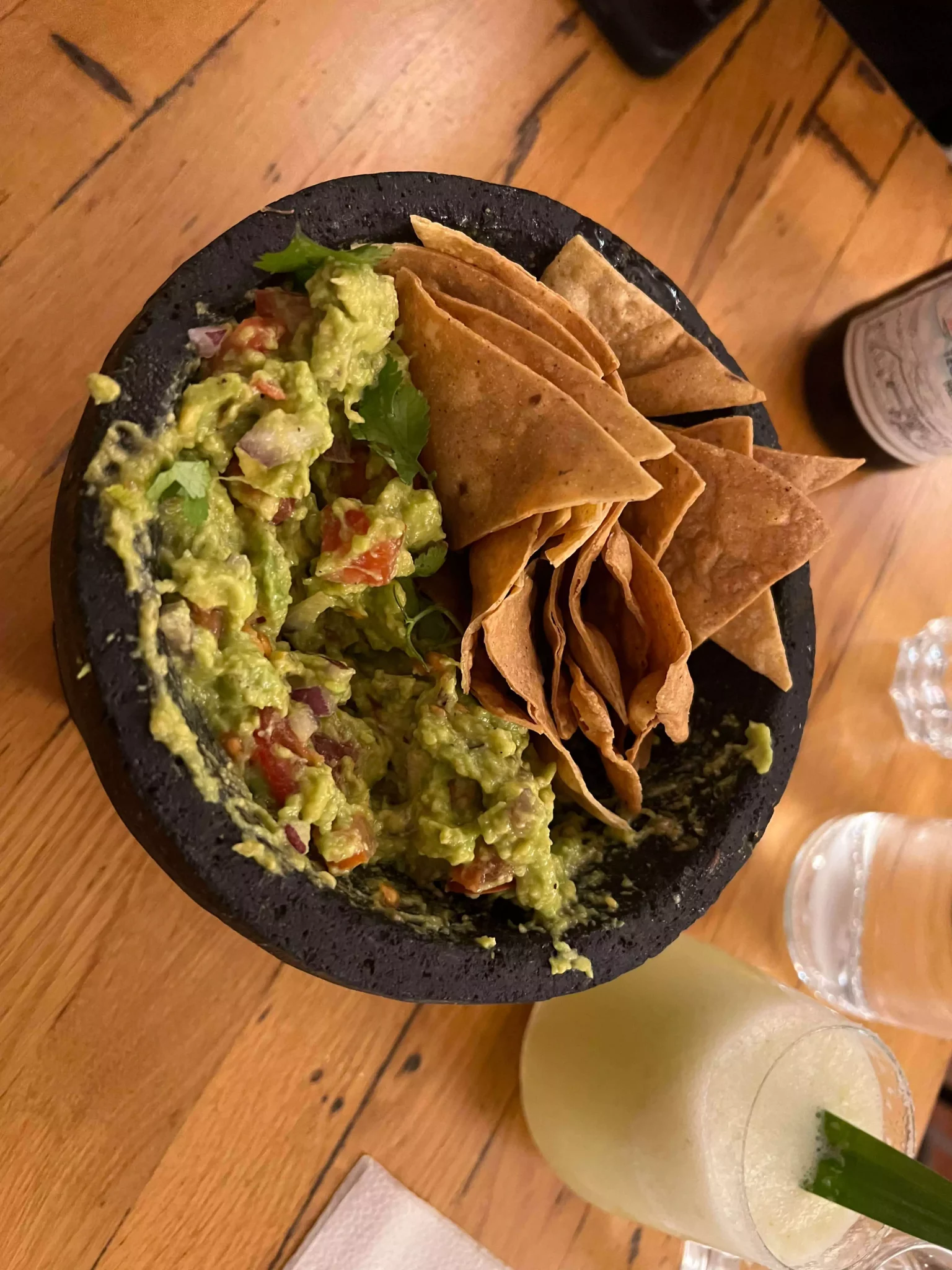Alt text: A bowl of fresh guacamole from Die Cabreras in Salzburg, Austria, served with a side of crispy tortilla chips. The creamy avocado dip is topped with diced tomatoes and herbs, offering a vibrant and flavorful appetizer.