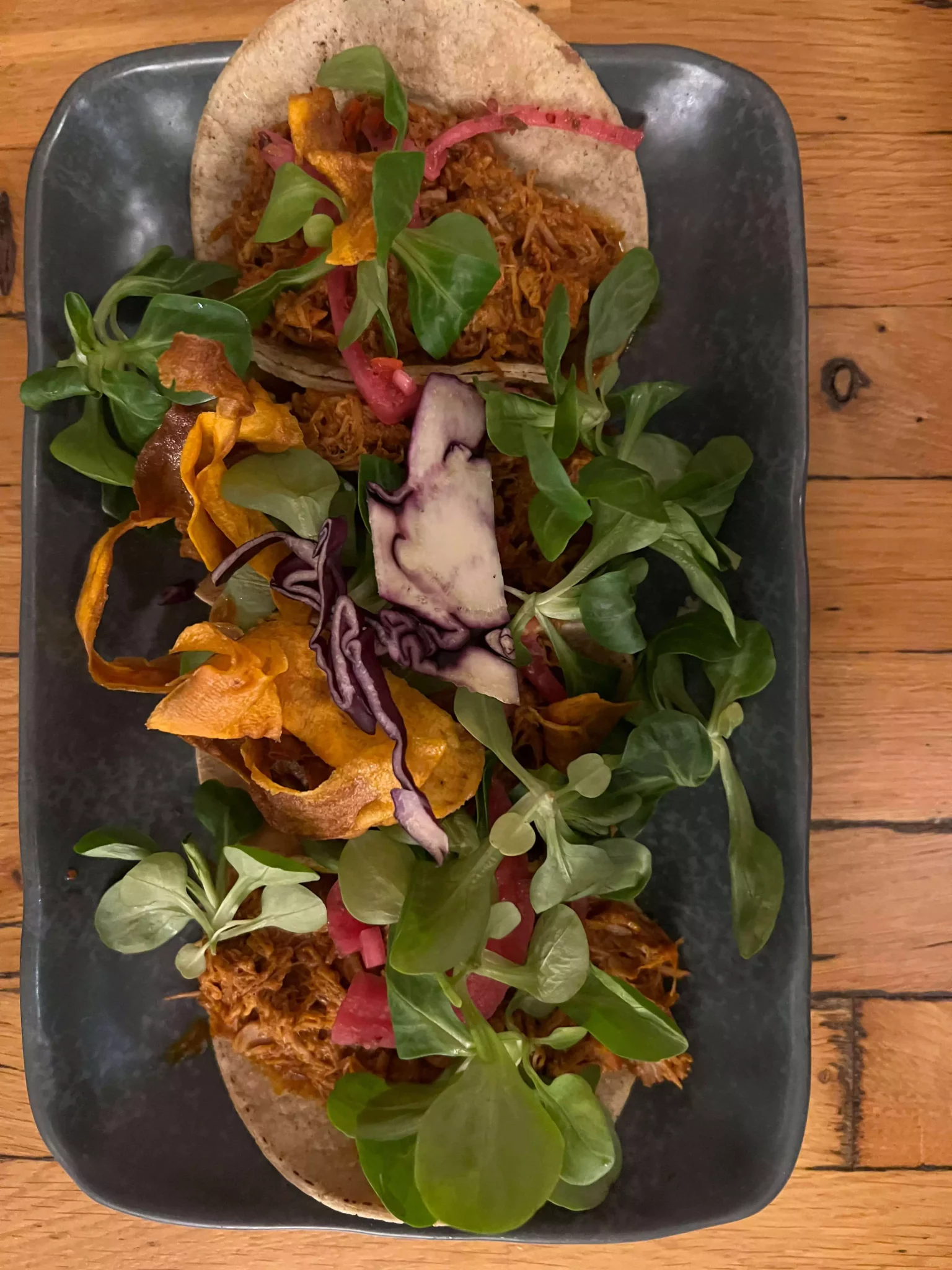 A plate of pork tacos served at Die Cabreras in Salzburg, Austria, featuring tender, seasoned meat topped with fresh onions, cilantro, and a wedge of lime. The colorful, street-style presentation adds a bold, flavorful twist to the local food scene.