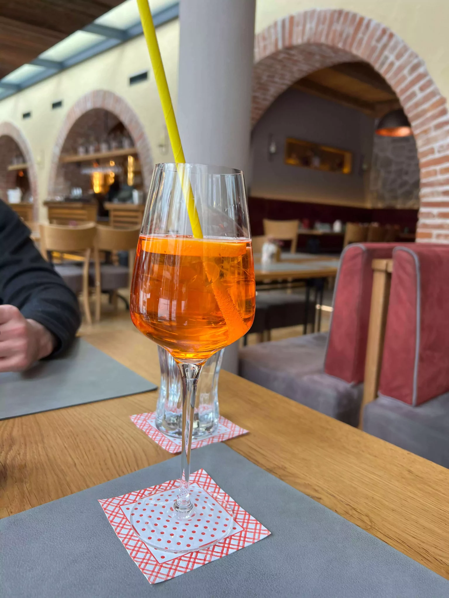 A refreshing Aperol Spritz served at La Stella in Salzburg, Austria, with its signature orange hue, ice cubes, and a slice of orange in a stemmed glass. The vibrant cocktail adds a cheerful touch to the relaxed Italian lunch setting.