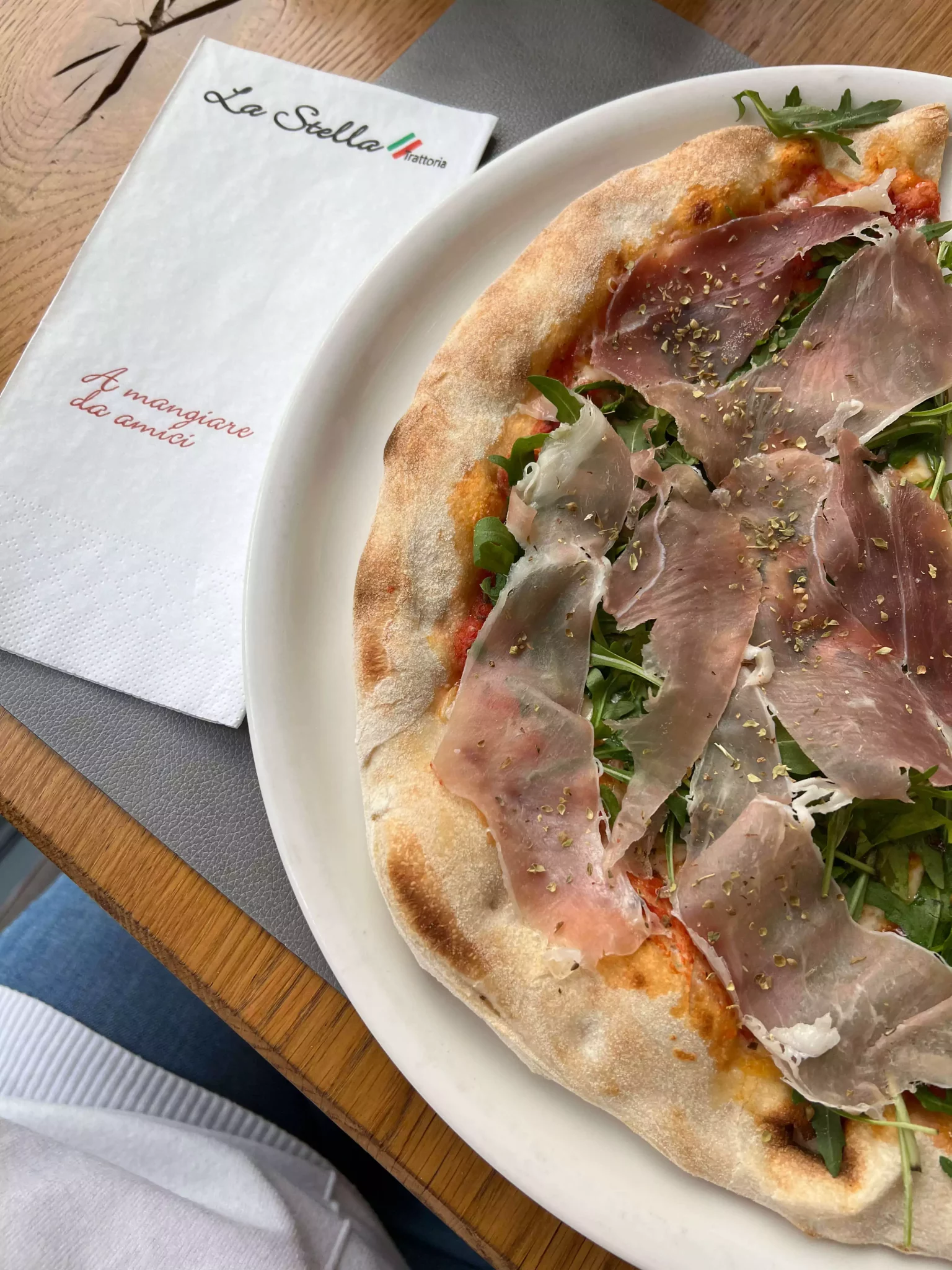 A prosciutto and arugula pizza served at La Stella in Salzburg, Austria, featuring thin slices of cured meat and fresh arugula atop a golden, wood-fired crust. The vibrant toppings and rustic presentation offer a classic Italian lunch with a fresh twist.