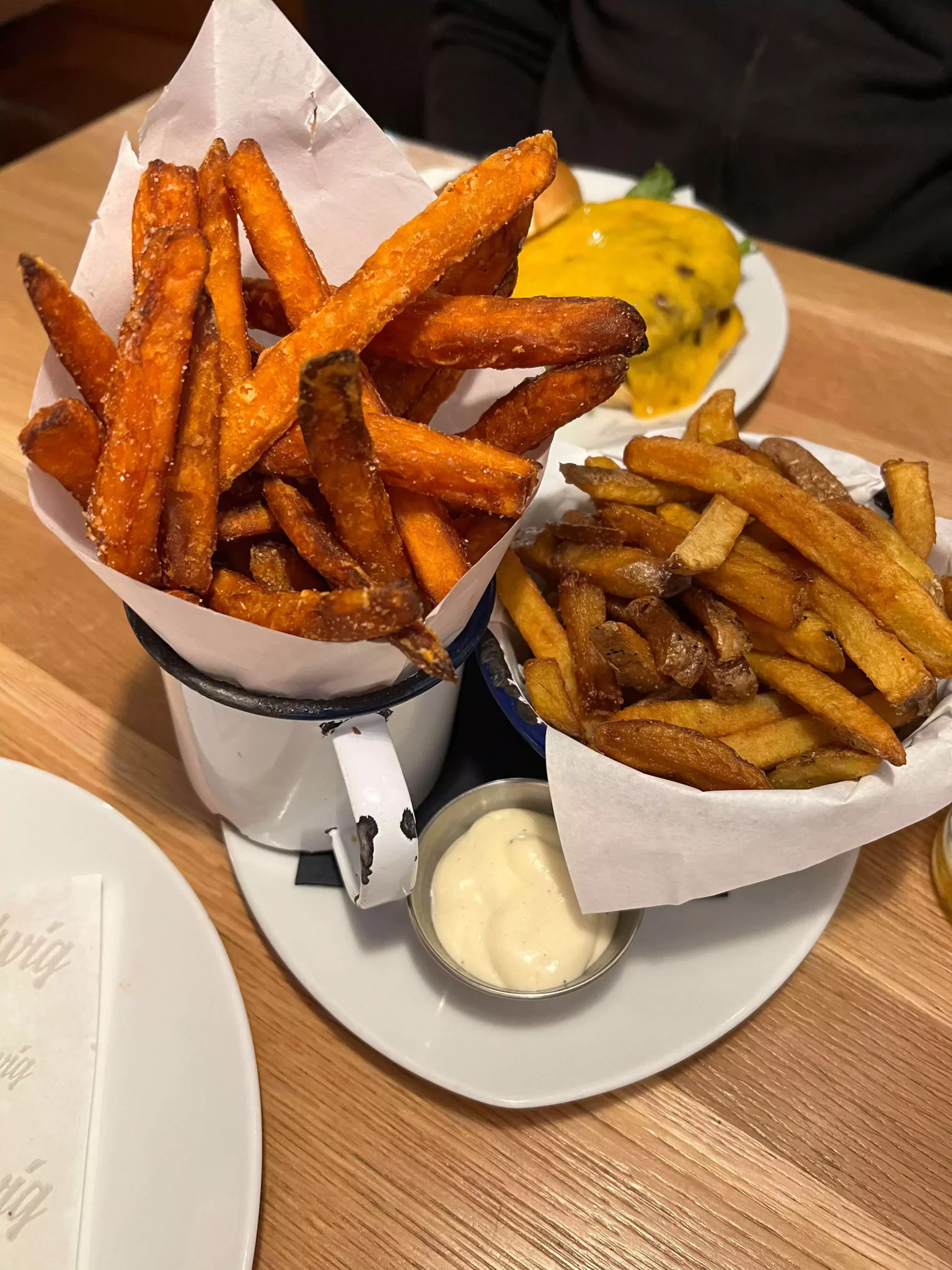 A duo of fries served at Ludwig in Salzburg, Austria, with one basket of golden regular fries and another of crispy sweet potato fries. The side-by-side presentation offers a tasty contrast of textures and flavors in a casual, comfort-food setting.